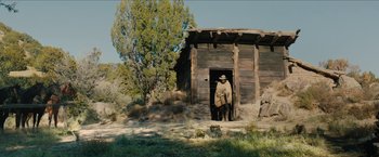 Movie still from “The Kid” (2019), directed by Vincent D'Onofrio – A man standing in front of an old wooden building; Extreme Wide shot, Low angle