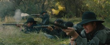 Movie still from “The Kid” (2019), directed by Vincent D'Onofrio – A group of people in the grass with guns; Medium shot, Over the shoulder angle