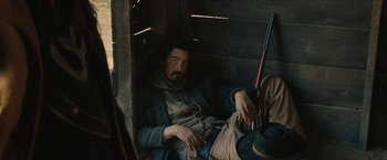 Movie still from “The Kid” (2019), directed by Vincent D'Onofrio – A man sitting in a chair with a rifle in his hand; Medium shot, High angle