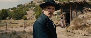 Movie still from “The Kid” (2019), directed by Vincent D'Onofrio – A man with a mustache wearing a black hat; Medium shot, Over the shoulder angle