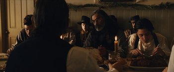 Movie still from “The Kid” (2019), directed by Vincent D'Onofrio – A group of people sitting at a table with a candle; Medium shot, Over the shoulder angle