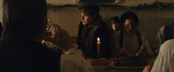 Movie still from “The Kid” (2019), directed by Vincent D'Onofrio – A group of people sitting at a table with a lit candle; Medium shot, Over the shoulder angle