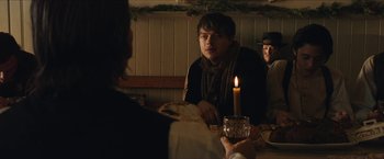 Movie still from “The Kid” (2019), directed by Vincent D'Onofrio – A man sitting at a dinner table with a candle; Medium shot, Over the shoulder angle