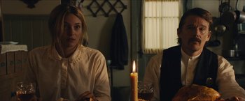 Movie still from “The Kid” (2019), directed by Vincent D'Onofrio – A woman sitting at a table next to a lit candle; Medium shot, Over the shoulder angle