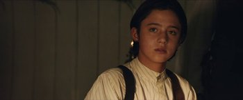 Movie still from “The Kid” (2019), directed by Vincent D'Onofrio – A young man wearing a shirt and suspenders in the dark; Close Up shot, Over the shoulder angle
