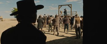 Movie still from “The Kid” (2019), directed by Vincent D'Onofrio – A crowd of people standing around a wooden device; Wide shot, Over the shoulder angle