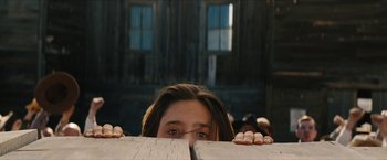 Movie still from “The Kid” (2019), directed by Vincent D'Onofrio – A woman hiding her face behind a wooden board; Close Up shot, Low angle