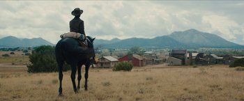 Movie still from “The Kid” (2019), directed by Vincent D'Onofrio – A man riding a horse through a field of dry grass; Extreme Wide shot, Low angle