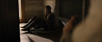 Movie still from “The Kid” (2019), directed by Vincent D'Onofrio – A man sitting on the ground in a room; Medium shot, Over the shoulder angle