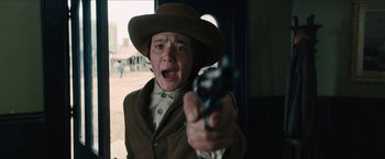 Movie still from “The Kid” (2019), directed by Vincent D'Onofrio – A young boy wearing a cowboy hat and holding a gun; Medium shot, Over the shoulder angle
