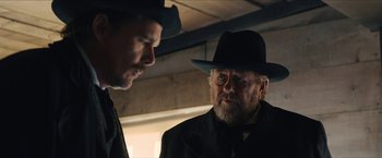 Movie still from “The Kid” (2019), directed by Vincent D'Onofrio – A man in a black hat and a man in a black suit; Close Up shot, Over the shoulder angle