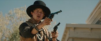 Movie still from “The Kid” (2019), directed by Vincent D'Onofrio – A man in a hat holding a pair of pistols; Medium shot, Low angle