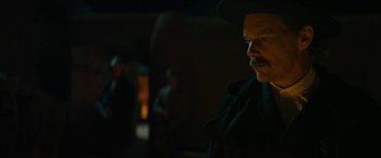 Movie still from “The Kid” (2019), directed by Vincent D'Onofrio – A man with a mustache and a hat is standing in the dark; Close Up shot, Over the shoulder angle