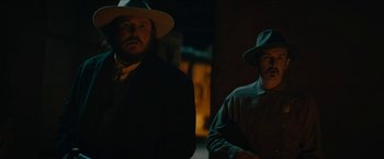 Movie still from “The Kid” (2019), directed by Vincent D'Onofrio – Two men standing next to each other in a dark room; Medium shot, Over the shoulder angle