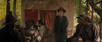 Movie still from “The Kid” (2019), directed by Vincent D'Onofrio – A man in a hat standing in front of a group of people; Medium shot, Over the shoulder angle