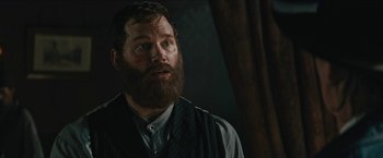 Movie still from “The Kid” (2019), directed by Vincent D'Onofrio – A man with a long beard is standing in a dark room; Close Up shot, Over the shoulder angle
