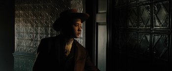 Movie still from “The Kid” (2019), directed by Vincent D'Onofrio – A man wearing a suit and hat in a dark room; Medium shot, Low angle