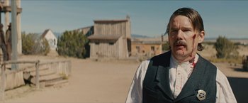 Movie still from “The Kid” (2019), directed by Vincent D'Onofrio – A man standing in front of an old western town; Medium shot, Over the shoulder angle
