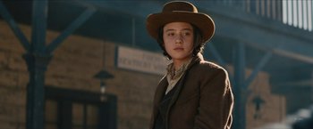 Movie still from “The Kid” (2019), directed by Vincent D'Onofrio – A woman in a brown hat and a brown jacket; Medium shot, Low angle