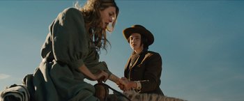 Movie still from “The Kid” (2019), directed by Vincent D'Onofrio – Two women sitting on the ground in a field; Medium shot, Low angle