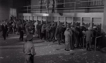 Movie still from “The Killing” (1956), directed by Stanley Kubrick – A crowd of people standing in front of an elevator; Wide shot, High angle