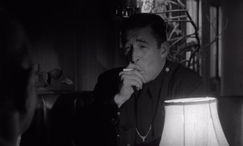 Movie still from “The Killing” (1956), directed by Stanley Kubrick – A black and white photo of a man smoking a cigarette; Close Up shot, Low angle