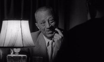 Movie still from “The Killing” (1956), directed by Stanley Kubrick – An older man sitting in a chair with a glass of wine; Close Up shot, Low angle