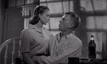 Movie still from “The Killing” (1956), directed by Stanley Kubrick – A man and a woman standing next to each other in front of a window; Medium shot, Low angle