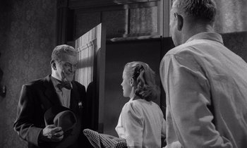 Movie still from “The Killing” (1956), directed by Stanley Kubrick – A group of people standing next to each other in a room; Medium shot, Over the shoulder angle