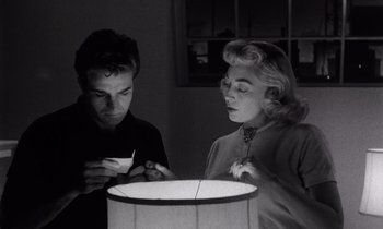 Movie still from “The Killing” (1956), directed by Stanley Kubrick – A man and a woman are looking at a lamp; Medium shot, Low angle