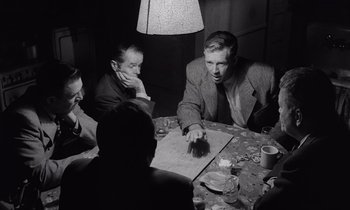 Movie still from “The Killing” (1956), directed by Stanley Kubrick – A group of people sitting around a table; Medium shot, Over the shoulder angle