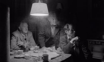 Movie still from “The Killing” (1956), directed by Stanley Kubrick – A group of men sitting at a table in front of a lamp; Medium shot, Low angle