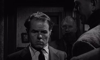 Movie still from “The Killing” (1956), directed by Stanley Kubrick – A black and white photo of a man in a suit and tie; Close Up shot, Over the shoulder angle