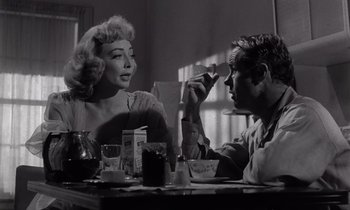 Movie still from “The Killing” (1956), directed by Stanley Kubrick – An old photo of two people sitting at a dinner table; Medium shot, Over the shoulder angle