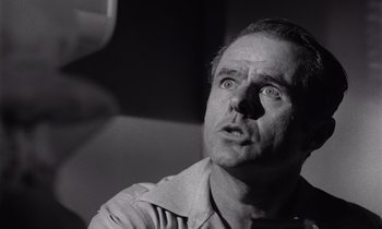 Movie still from “The Killing” (1956), directed by Stanley Kubrick – A man looking up into the air with a surprised look on his face; Close Up shot, Low angle