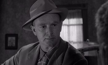 Movie still from “The Killing” (1956), directed by Stanley Kubrick – An older man wearing a suit and a hat; Close Up shot, Over the shoulder angle