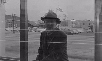 Movie still from “The Killing” (1956), directed by Stanley Kubrick – An older man wearing a hat looking out of a window; Medium shot, Low angle