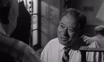Movie still from “The Killing” (1956), directed by Stanley Kubrick – An older man wearing a neck tie talking to someone; Close Up shot, Over the shoulder angle