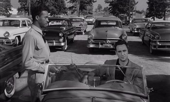 Movie still from “The Killing” (1956), directed by Stanley Kubrick – A man and a woman sitting in the back of an antique car; Medium shot, Over the shoulder angle