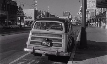 Movie still from “The Killing” (1956), directed by Stanley Kubrick – An old car parked on the side of the road; Wide shot, Low angle