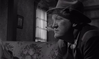 Movie still from “The Killing” (1956), directed by Stanley Kubrick – A black and white photo of a man smoking a cigarette; Close Up shot, Low angle