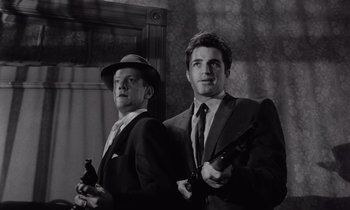 Movie still from “The Killing” (1956), directed by Stanley Kubrick – A black and white photo of two men holding guns; Medium shot, Low angle