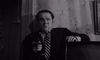 Movie still from “The Killing” (1956), directed by Stanley Kubrick – A man in a suit and tie holding a nintendo wii controller; Medium shot, Low angle