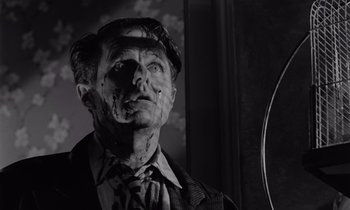 Movie still from “The Killing” (1956), directed by Stanley Kubrick – A man in a suit and tie looking at a mirror; Close Up shot, Low angle