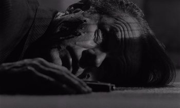 Movie still from “The Killing” (1956), directed by Stanley Kubrick – A man laying on the ground with his head on the ground; Close Up shot, Low angle