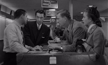 Movie still from “The Killing” (1956), directed by Stanley Kubrick – A group of people sitting around a table; Medium shot, Over the shoulder angle