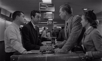 Movie still from “The Killing” (1956), directed by Stanley Kubrick – A group of men sitting at a table talking to each other; Medium shot, Over the shoulder angle