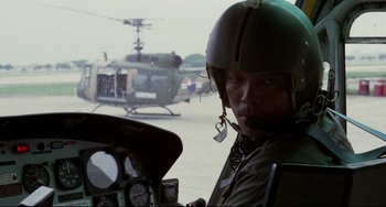 Movie still from “The Killing Fields” (1984), directed by Roland Joffé – A man in a helicopter cockpit with a helicopter in the background; Close Up shot, Low angle
