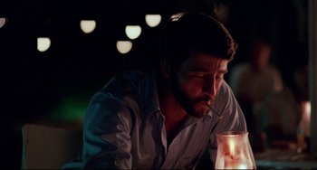 Movie still from “The Killing Fields” (1984), directed by Roland Joffé – A man sitting at a table with a cigarette in his mouth; Close Up shot, Over the shoulder angle