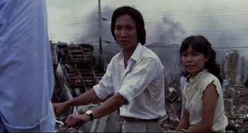 Movie still from “The Killing Fields” (1984), directed by Roland Joffé – A man riding a bike next to a woman in a white shirt; Medium shot, Low angle